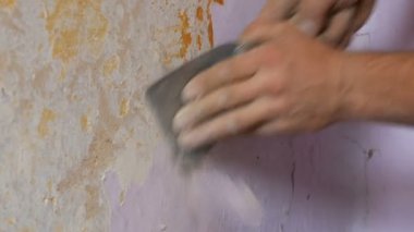 Bir duvar, ev onarım eli ayağı tutmaz pembe duvar kağıdı. Özel spatula ile eski duvar kağıdı soyulması adam.