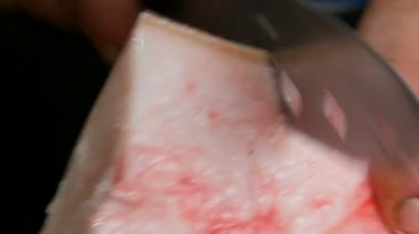 Erkek kasap taze domuz eti büyük bir parçası büyük bir bıçakla keser. Domuz yağı ile et ve deri görünümü kapatın