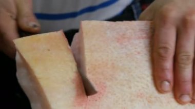 Erkek kasap taze domuz eti büyük bir parçası büyük bir bıçakla keser. Domuz yağı ile et ve deri görünümü kapatın