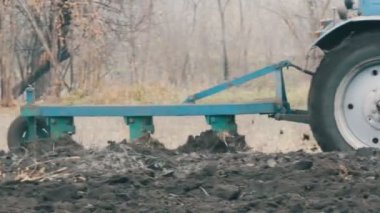 Mavi traktör ile siyah toprakla tarlayı dört karık plough görünümü kapatın