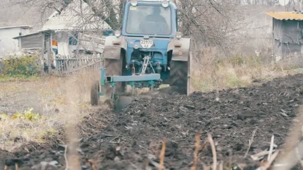 Голубой трактор с четырьмя бороздками плужного поля с черной почвой крупным планом — стоковое видео