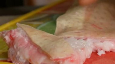 Erkek kasap taze domuz eti büyük bir parçası büyük bir bıçakla keser. Domuz yağı ile et ve deri görünümü kapatın