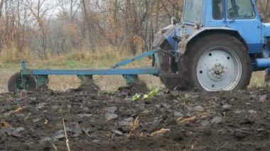 Mavi bir traktör siyah toprak derin sonbaharda pulluk. Kış zemin hazırlama