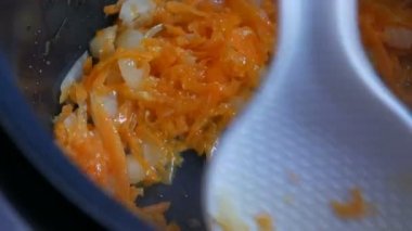 Havuç ve soğan tavada kavrulmuş. Beyaz mutfak spatula sebze karıştırma. Vejetaryen yiyecekler