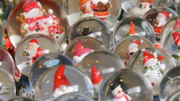 Beaucoup de boules de neige décoratives ou de boules de Noël avec le Père Noël à l'intérieur. Décor de Noël et Nouvel An pour la maison sur le comptoir du marché de Noël — Video