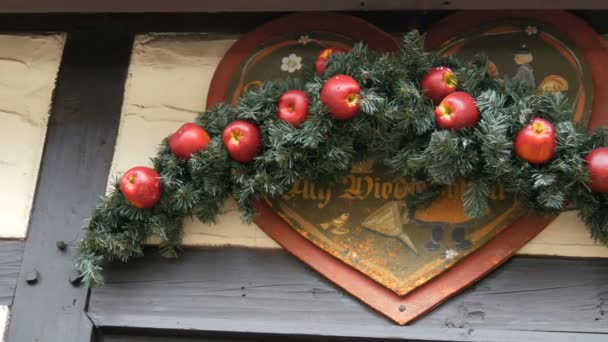 De kroon van de spar van Kerstmis met rode appels boven de ingang voor het opslaan van de Duitse kerstmarkt, met het opschrift in Duitse vaarwel — Stockvideo