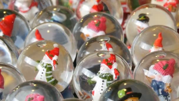 Lot of decorative snow globe or Christmas balls with Santa Claus inside. Christmas and New Years decor for the home on the counter of the Christmas market — Stock Video