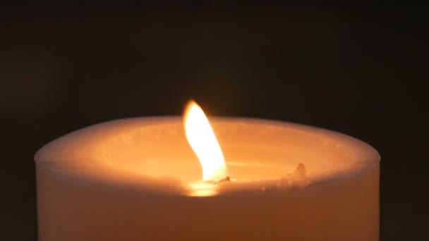 Большая белая горящая свеча в темноте. Пламя свечи в ночное время — стоковое видео
