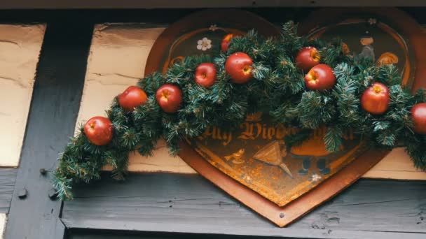 Christmas fir wreath with red apples over the entrance to store of the German Christmas market, with the inscription in German goodbye — Stock Video