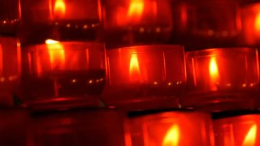 Katolik Kilisesi içinde yanan memorial mumlar. Satır Hıristiyan dua kırmızı yuvarlak Adak mumları yanık içinde belgili tanımlık karanlık. Kurban mum dua kapatın. Katedralde Noel kutlamaları
