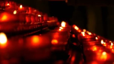 Satır Hıristiyan dua kırmızı yuvarlak Adak mumları yanık içinde belgili tanımlık karanlık. Kurban mum dua görünümü kapatın. Katolik Kilisesi içinde yanan memorial mumlar. Katedralde Noel kutlamaları
