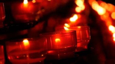 Katolik Kilisesi içinde yanan memorial mumlar. Satır Hıristiyan dua kırmızı yuvarlak Adak mumları yanık içinde belgili tanımlık karanlık. Kurban mum dua kapatın. Katedralde Noel kutlamaları