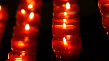 Satır Hıristiyan dua kırmızı yuvarlak Adak mumları yanık içinde belgili tanımlık karanlık. Kurban mum dua kapatın. Katolik Kilisesi içinde yanan memorial mumlar. Katedralde Noel kutlamaları