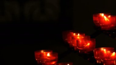 Satır Hıristiyan dua kırmızı yuvarlak Adak mumları yanık içinde belgili tanımlık karanlık. Kurban mum dua kapatın. Katolik Kilisesi içinde yanan memorial mumlar. Katedralde Noel kutlamaları