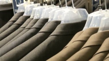 Kahverengi ve gri erkek ceket askı erkek giyim mağazası alışveriş merkezinde dayan. Erkek takım elbise askıları alışveriş merkezinde yakın bakış üzerinde büyük bir aralığı