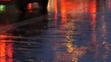 Arabalar trafikte, farlardan asfalt, yağmur altında görüntüleyin. Yağmur su birikintileri geceleri vurur. Arabalar ışıkların yansıması
