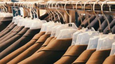 Kahverengi ve gri erkek ceket askı erkek giyim mağazası alışveriş merkezinde dayan. Erkek takım elbise askıları yakın görünümü kadar alışveriş merkezinde üzerinde büyük bir aralığı