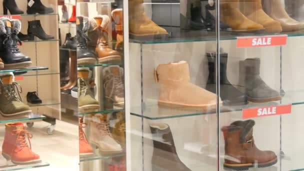 Γυάλινη βιτρίνα κατάστημα παπουτσιών στον οποίο η επιγραφή πώληση. Κομψά παπούτσια Φθινόπωρο-Χειμώνας στον πάγκο της η ακριβά βιτρίνα. Διάφορες μπότες μόδα με έκπτωση — Αρχείο Βίντεο