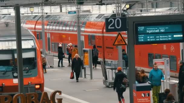 Múnich, Alemania - 2 de diciembre de 2018: Los turistas pasajeros caminan a lo largo de la plataforma junto al moderno tren rojo en la estación principal de tren — Vídeos de Stock