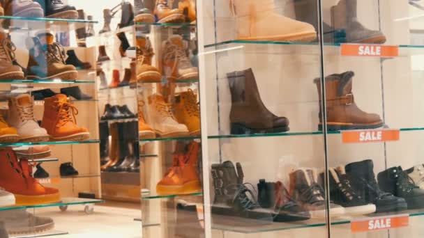 Vitrine de vidro sapato loja em que a venda inscrição. Sapatos de outono-inverno elegantes no balcão da loja cara. Várias botas de moda com desconto — Vídeo de Stock
