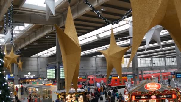 Monachium - zm. 2 grudnia 2018: Stacja kolejowa przed świętami Bożego Narodzenia. Pięknie urządzone na Boże Narodzenie stacji, gdzie ludzie są zatłoczone. Duża złota i srebra Boże Narodzenie gwiazdy na suficie widok z góry — Wideo stockowe