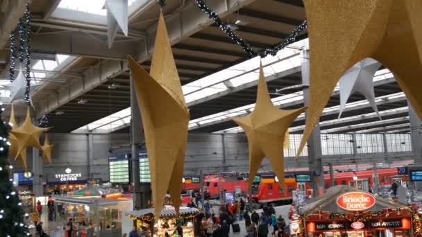 Munique, Alemanha - 2 de dezembro de 2018: Estação ferroviária antes do Natal. Belamente decorado para a estação de Natal, onde as pessoas estão lotadas. Grandes estrelas de Natal de ouro e prata na vista superior do teto — Vídeo de Stock