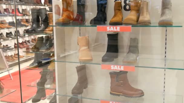 Γυάλινη βιτρίνα κατάστημα παπουτσιών στον οποίο η επιγραφή πώληση. Κομψά παπούτσια Φθινόπωρο-Χειμώνας στον πάγκο της η ακριβά βιτρίνα. Διάφορες μπότες μόδα με έκπτωση — Αρχείο Βίντεο