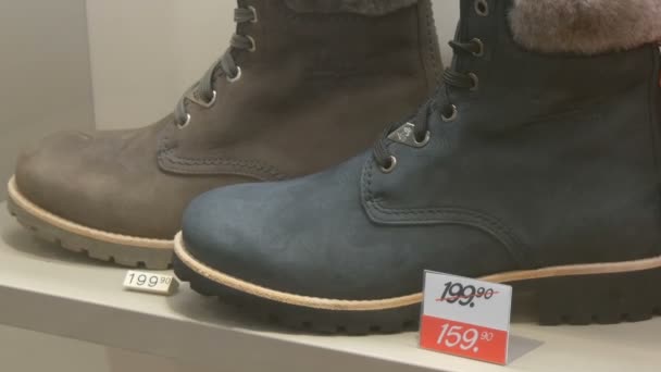 München, Deutschland - 2. Dezember 2018: Teure Luxusstiefel im Schuhgeschäft neben dem Discount-Preisschild Großaufnahme — Stockvideo