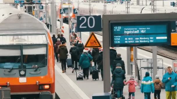 Mnichov, Německo - 2. prosince 2018: Turisté cestující procházka podél platforma vedle moderní červený vlak na hlavním nádraží v vánoční dárky — Stock video