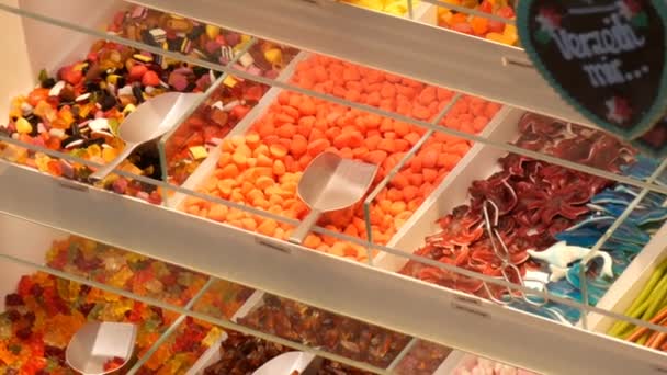 Karışık renkli jöle şekerler bir gıda pazarı mağazasında Alman şeker adları, sayaçta şeker ağırlığında olan kürek — Stok video
