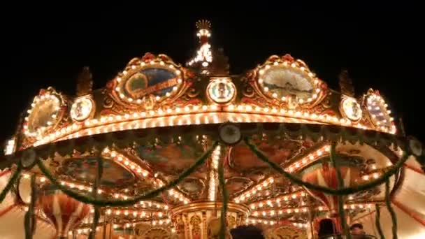 Nuremberg, Germany - December 1, 2018: Fascinating flashing lights dark night sky illumination of vintage merry go round fair carousel ferris wheel in christmas market — Stock Video