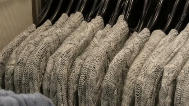 Modieuze collectie warme kleren. Groot aantal nieuwe warme stijlvolle truien van verschillende kleuren opknoping op hangers in de kleding bewaren shopping center of mall. — Stockvideo