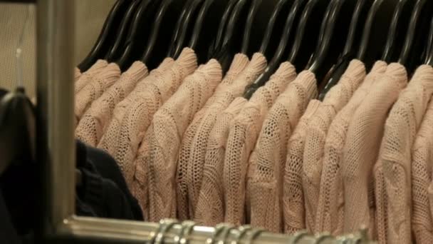Coleção na moda de roupa quente. Grande número de novas camisolas elegantes quentes de cores diferentes penduradas em cabides no centro comercial da loja de roupas ou shopping . — Vídeo de Stock