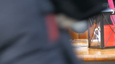 Erkek ve bir kadın sokak bir kafede kahve içiyor. Bir adam bir çay kaşığı kahve kıpırdanırken, sokakta bir şamdan ile rahat tabloya göre insanlar geçer