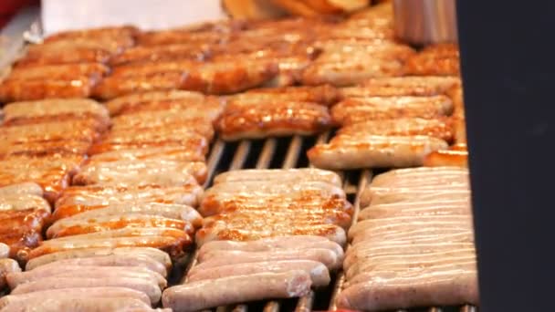 Un montón de deliciosas salchichas alemanas a la parrilla Nuremberg a la parrilla en fila en el mercado de Navidad, mujer se convierte en salchichas fritas — Vídeos de Stock