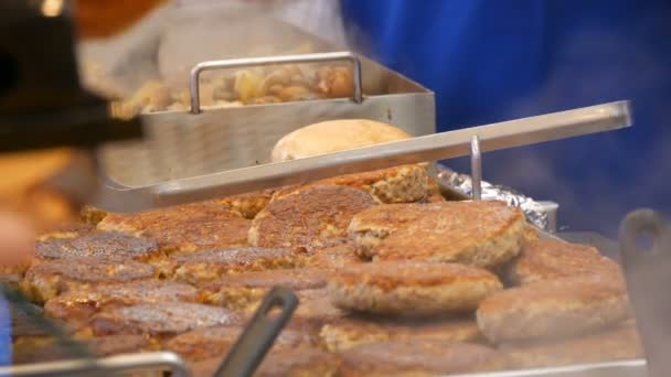 Grandi costolette di hamburger alla griglia sono venduti sul bancone del chiosco stradale. Molte polpette appena cotte sono sul bancone del mercatino di Natale. venditore restituisce denaro al compratore — Video Stock