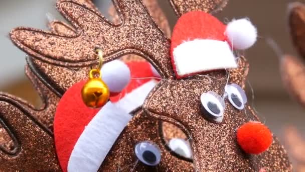 Año Nuevo y aros de Navidad en la cabeza en forma de ciervos en los sombreros de Santa Claus y campana en la oreja vista de cerca. El espíritu de la Navidad y Año Nuevo — Vídeo de stock