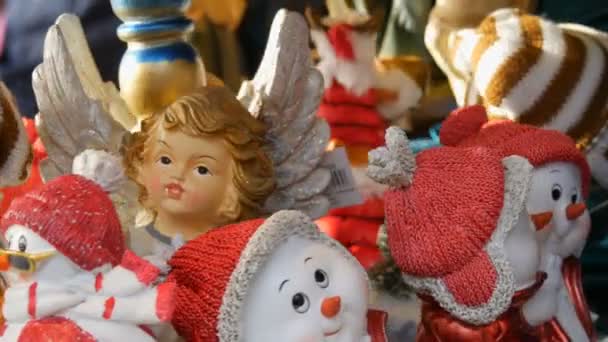 Navidad y Año Nuevo estatuas de juguete en forma de ángeles, ciervos, muñecos de nieve en los sombreros de Santa Claus que están girando en el mostrador del mercado de Navidad — Vídeos de Stock