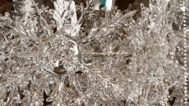 A beautiful windmill Christmas glass toy in the shape of a large snowflake sways in the wind at the counter with Christmas and New Year decorations, the close up view — Stock Video