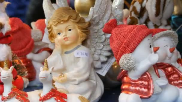 Jul og nytår legetøj statuer i form af engle, hjorte, snemænd i Santa Claus hatte, der spinner på tælleren af julemarkedet – Stock-video