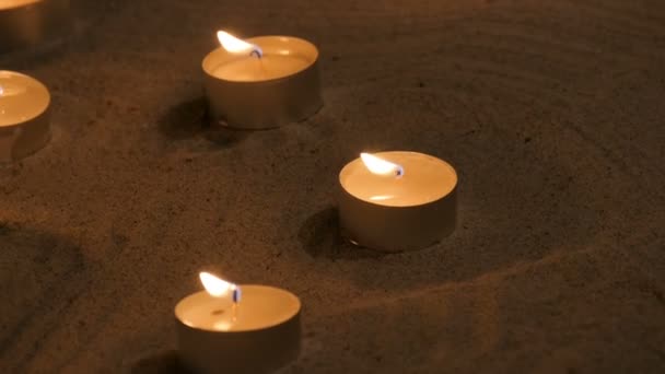 Много маленьких горящих свечей на песке в храме — стоковое видео