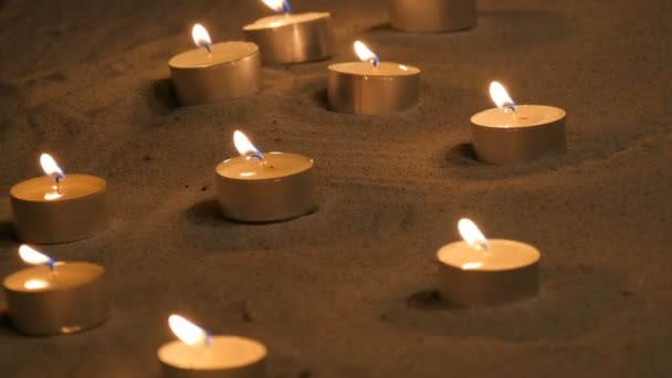 Muchas pequeñas velas encendidas en la arena en el templo — Vídeos de Stock