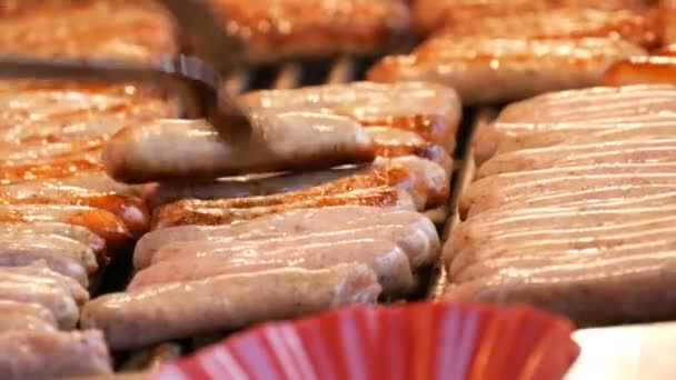Много вкусных Нюрнбергских сосисок на гриле подряд на Рождественской ярмарке, женщина делает жареные сосиски — стоковое видео