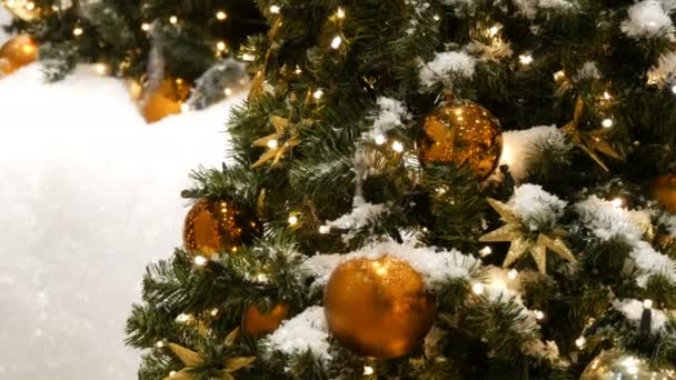 Árbol de Navidad bellamente decorado con grandes bolas de oro y plata, estrellas, guirnaldas y nieve artificial está de pie en el centro comercial vista de cerca — Vídeo de stock