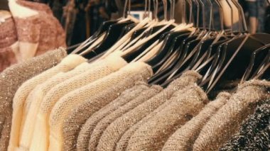 Güzel sıcak bayan kabarık kazak gri, siyah ve beyaz satır alışveriş merkezinin veya alışveriş merkezi deposundaki siyah askı üzerinde asılı. Sıcak giysiler moda koleksiyonu.