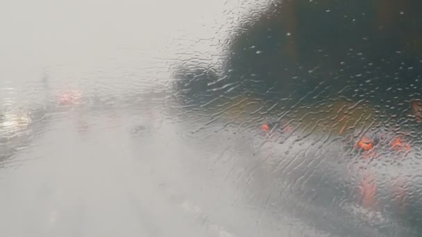Primer plano de gotas de lluvia y rayas en la ventana od autobús en movimiento por la calle de la ciudad en otoño profundo — Vídeo de stock