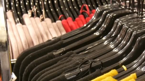 Различные стильные вязаные разноцветные свитера, висящие на черных вешалках моды в магазине одежды в торговом центре или торговом центре — стоковое видео