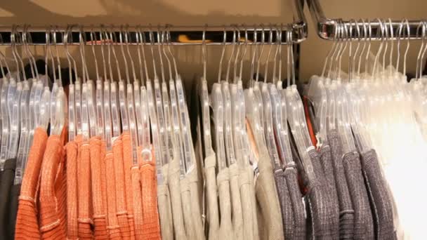 Διάφορα πολύχρωμα Γυναικεία ρούχα που κρέμονται στις κρεμάστρες σε ένα κατάστημα ενδυμάτων στη λεωφόρο ή το εμπορικό κέντρο — Αρχείο Βίντεο