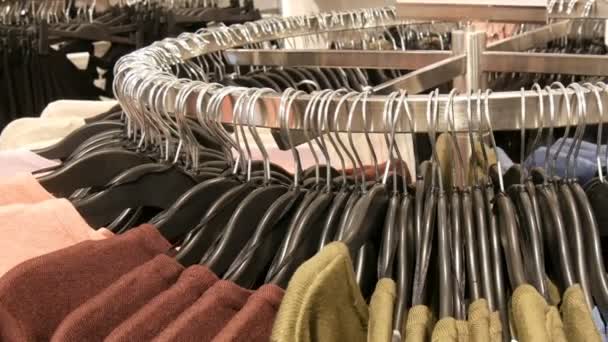 다양 한 세련 된 니트 다 색된 스웨터 쇼핑몰 이나 쇼핑 센터에서 옷이 게에서 블랙 패션 옷걸이에 걸려 있다 큰 라운드 걸이에서 볼을 닫습니다 — 비디오