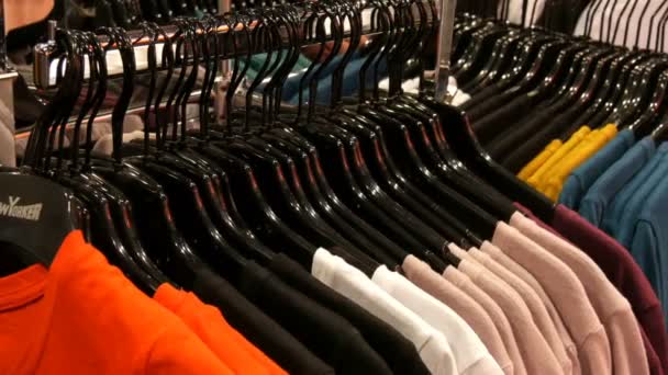 Nuremberg, Alemanha - 3 de dezembro de 2018: Várias roupas penduradas em cabides pretos de moda em uma loja de roupas no shopping ou centro comercial — Vídeo de Stock